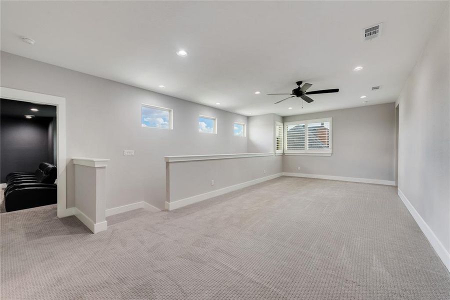 Unfurnished room featuring ceiling fan, light colored carpet, and plenty of natural light