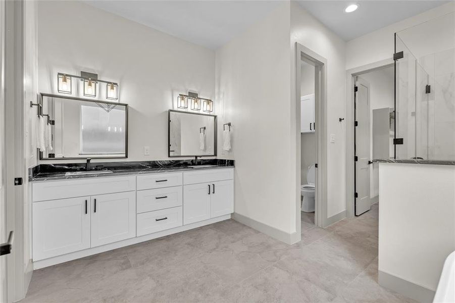 Spacious ensuite bathroom with double sinks, granite countertops, separate framed mirrors