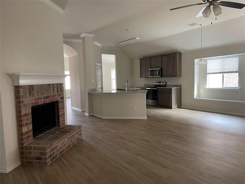 Kitchen with light wood-type flooring, ceiling fan, light stone counters, and stainless steel appliances