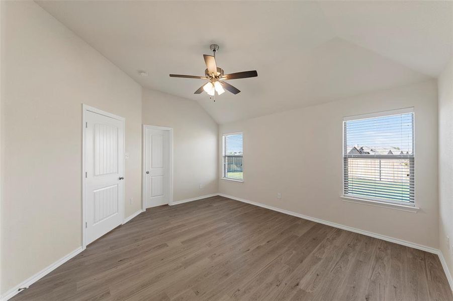 Unfurnished room featuring a wealth of natural light, lofted ceiling, ceiling fan, and hardwood / wood-style flooring