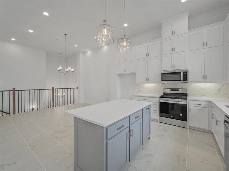 Kitchen with a kitchen island, appliances with stainless steel finishes, white cabinetry, and pendant lighting