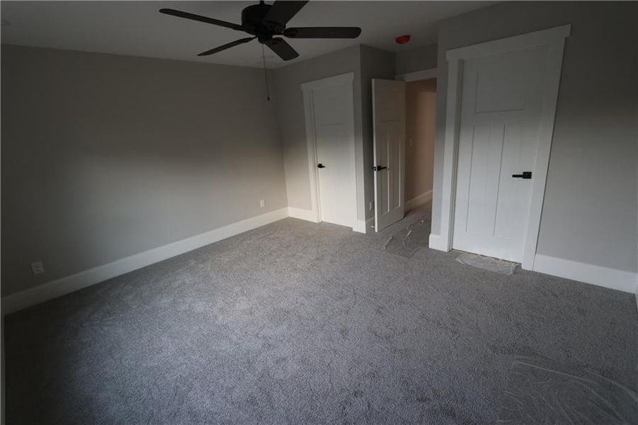 Unfurnished bedroom with ceiling fan and carpet flooring