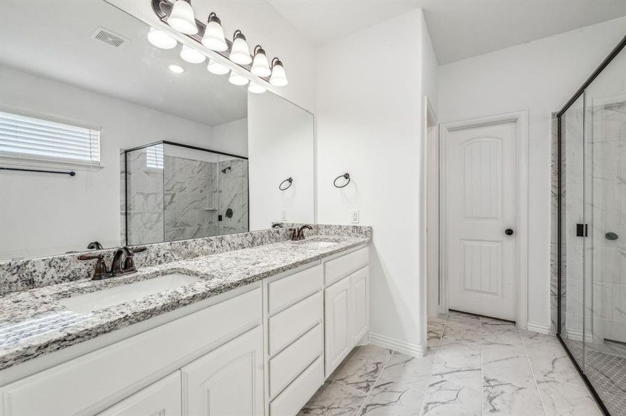 Bathroom featuring tile patterned flooring, double sink vanity, and a shower with door