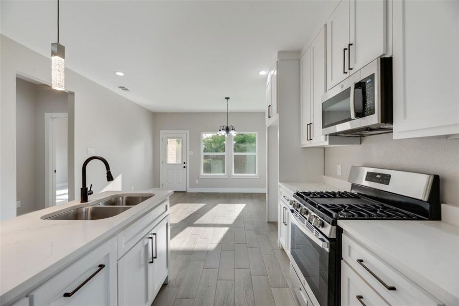 Kitchen featuring sink, light hardwood / wood-style flooring, white cabinetry, and stainless steel appliances