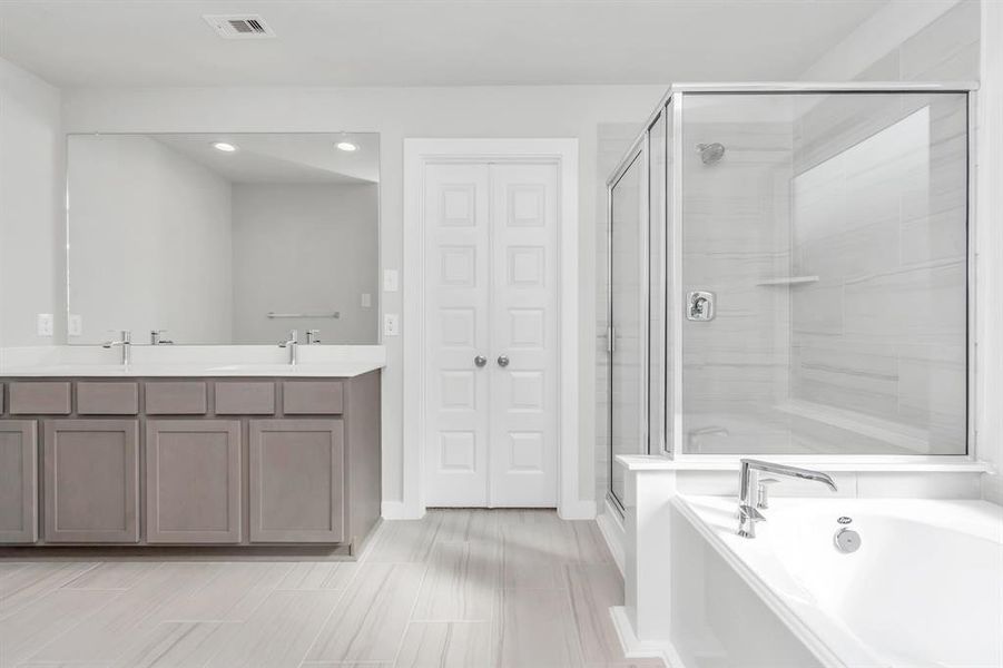 This additional view of the primary bath features a walk-in shower with the tile surround and separate garden tub perfect for soaking after a long day. Sample photo of completed home with similar floor plan. As-built interior colors and selections may vary.