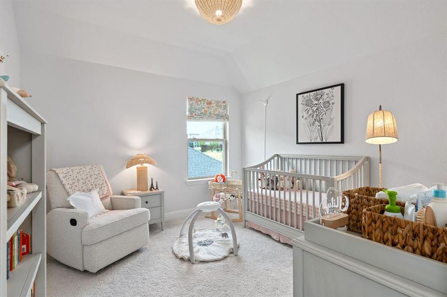 Bedroom featuring a crib, vaulted ceiling, and carpet flooring