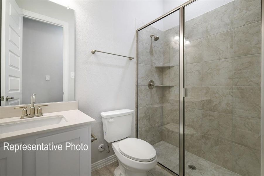 Bathroom featuring a shower with shower door, toilet, and vanity