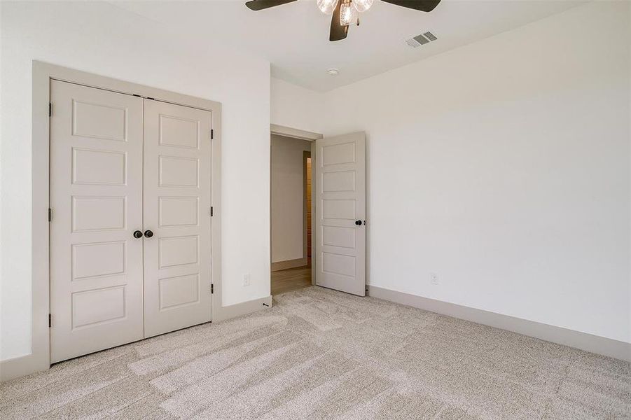 Unfurnished bedroom with a closet, ceiling fan, and light carpet