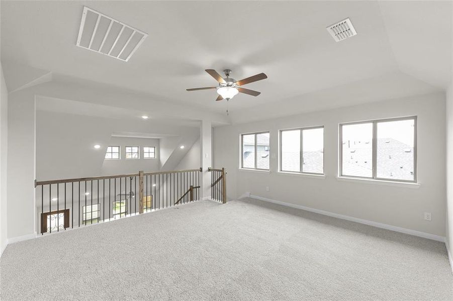 Unfurnished room featuring carpet, ceiling fan, and plenty of natural light