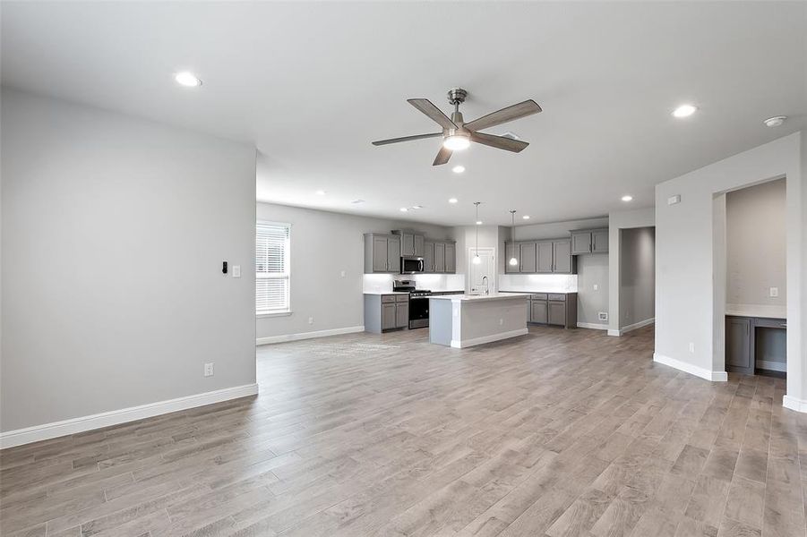 Unfurnished living room featuring sink, light hardwood / wood-style floors, and ceiling fan