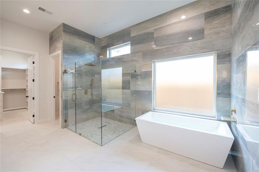 Bathroom with tile floors, shower with separate bathtub, and tile walls
