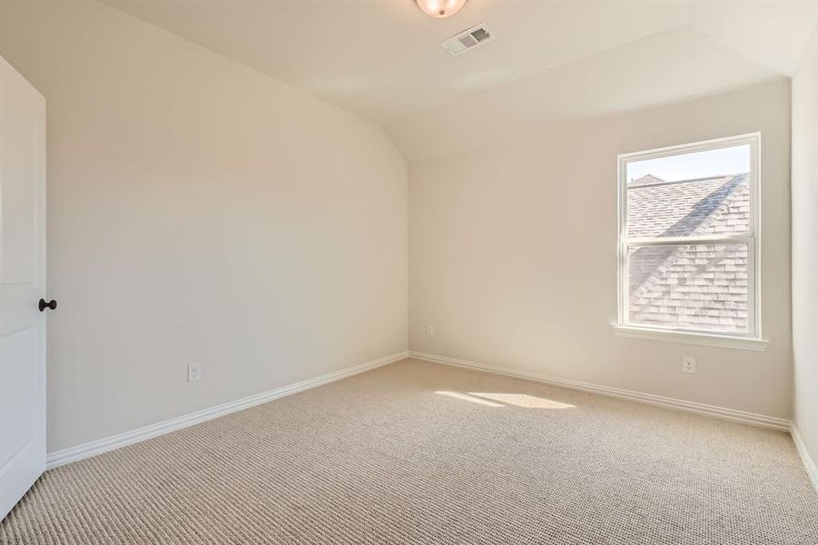 Carpeted spare room with vaulted ceiling