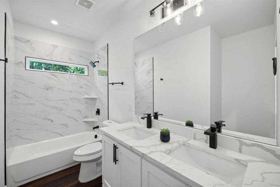 Full bathroom featuring hardwood / wood-style flooring, tiled shower / bath, toilet, and dual bowl vanity