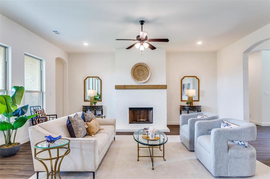 Living room with light wood-type flooring, ceiling fan, and a fireplace