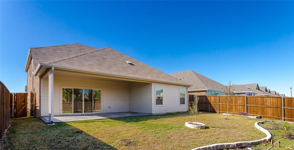 Rear view of house featuring a patio lots of green space.