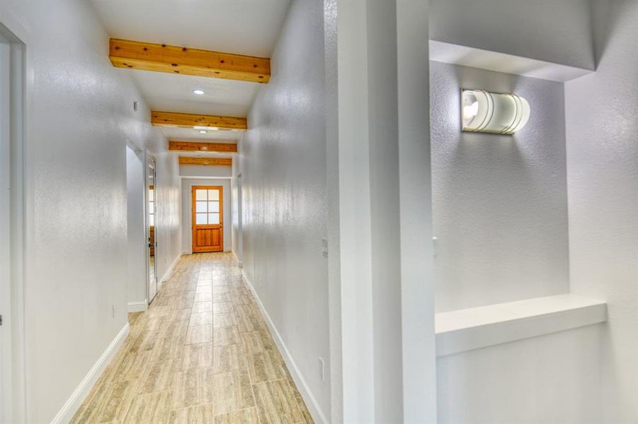 Corridor with beam ceiling and light hardwood / wood-style floors