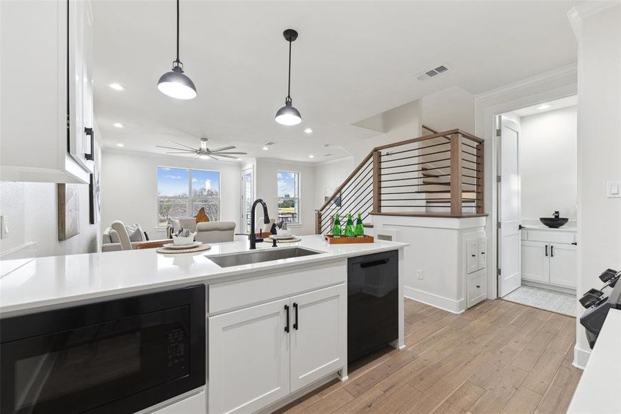 Kitchen with white cabinetry, black appliances, ceiling fan, sink, and light hardwood / wood-style flooring