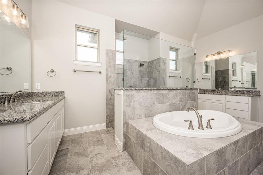 Bathroom with tile patterned flooring, a healthy amount of sunlight, vaulted ceiling, and vanity