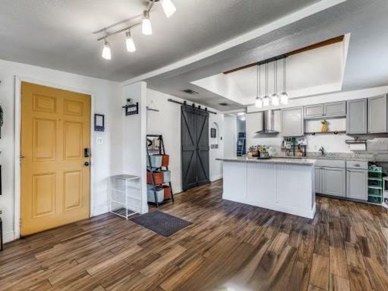 Kitchen with gray cabinets, dark wood-type flooring, ventilation hood, and a barn door