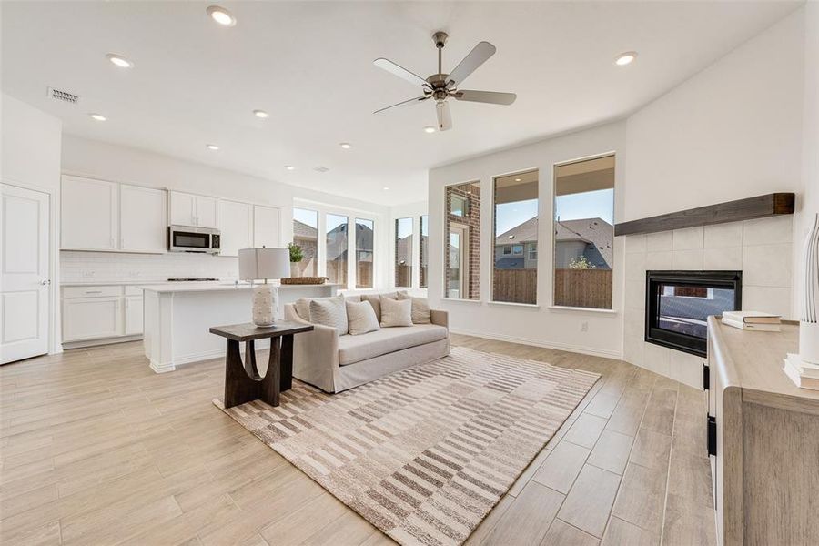 Living room featuring light hardwood / wood-style flooring, ceiling fan, and a tile fireplace