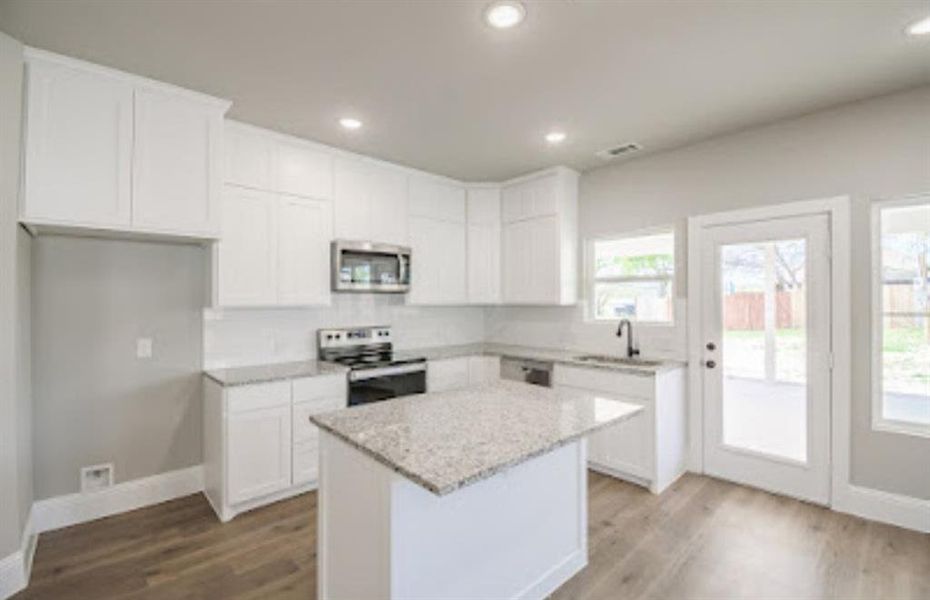Kitchen featuring appliances with stainless steel finishes, white cabinetry, and a kitchen island