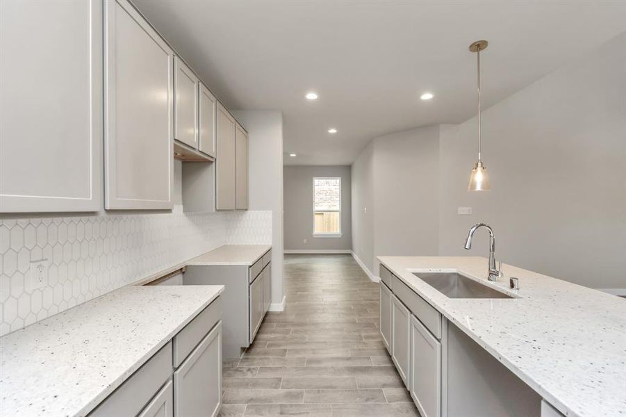 Discover another perspective of this stunning kitchen, generously appointed with an abundance of counter space. Sample photo of completed home with similar floor plan. As built color and selections may vary.