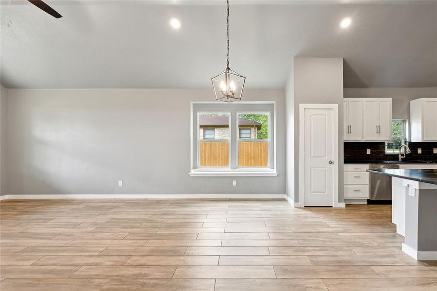 Kitchen featuring ceiling fan with notable chandelier, dishwasher, light hardwood / wood-style flooring, hanging light fixtures, and white cabinetry