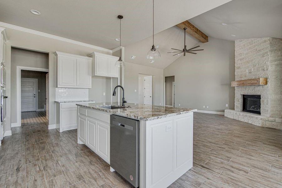 Kitchen with white cabinets, a fireplace, appliances with stainless steel finishes, beamed ceiling, and sink