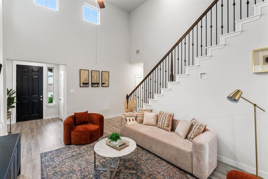 Living room with a towering ceiling and hardwood / wood-style flooring