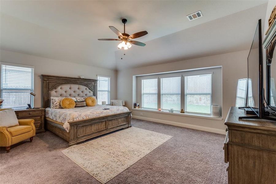 Bedroom featuring multiple windows, carpet, vaulted ceiling, and ceiling fan