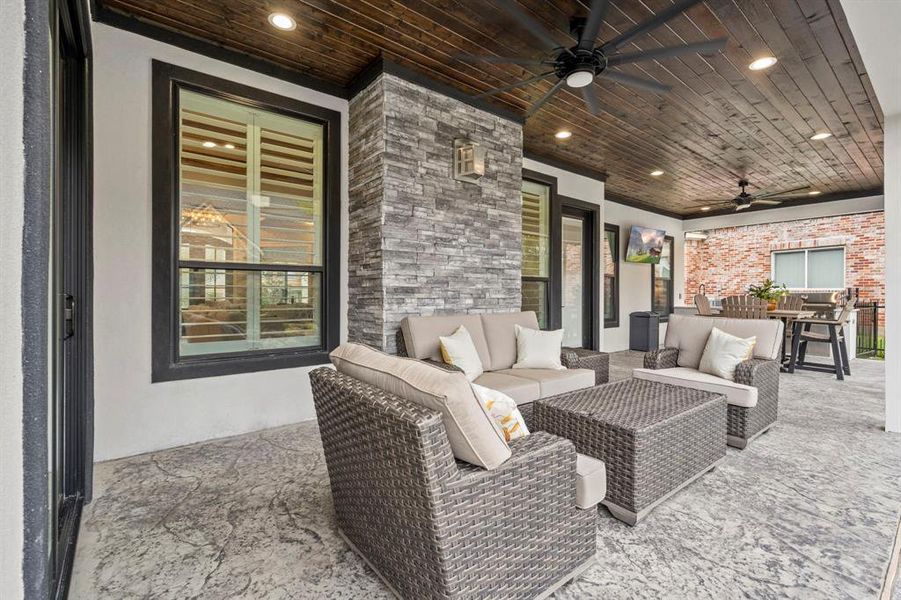 Expansive, covered back patio features outdoor kitchen, wood ceiling, two ceiling fans, stamped and stained concrete with two access entries to the home