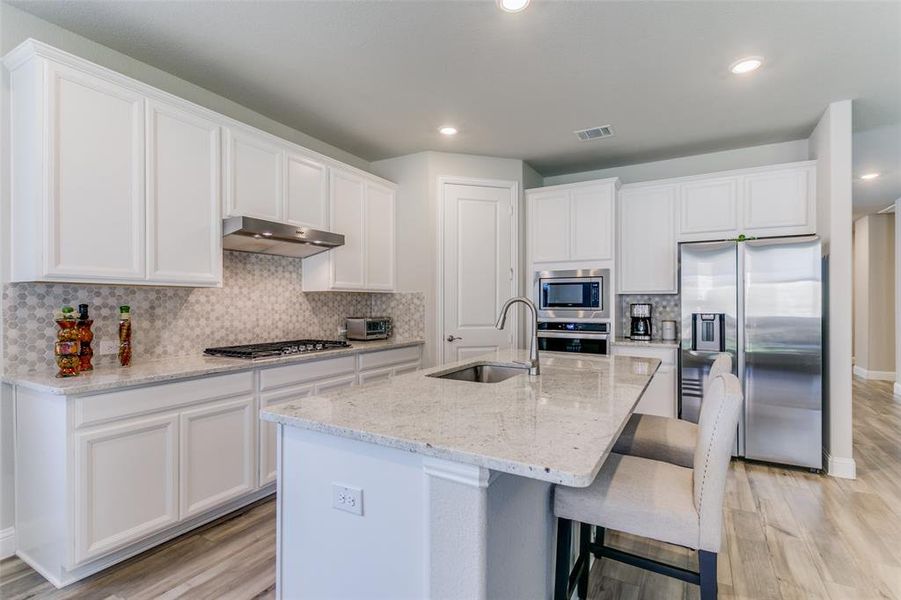 Kitchen with an island with sink, stainless steel appliances, tasteful backsplash, and sink