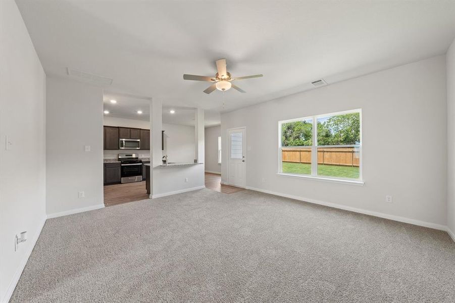 Unfurnished living room featuring ceiling fan and light carpet