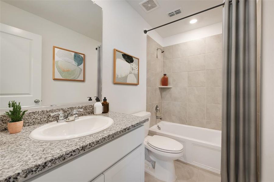 Full bathroom with tile floors, toilet, shower / bath combo, and vanity with extensive cabinet space