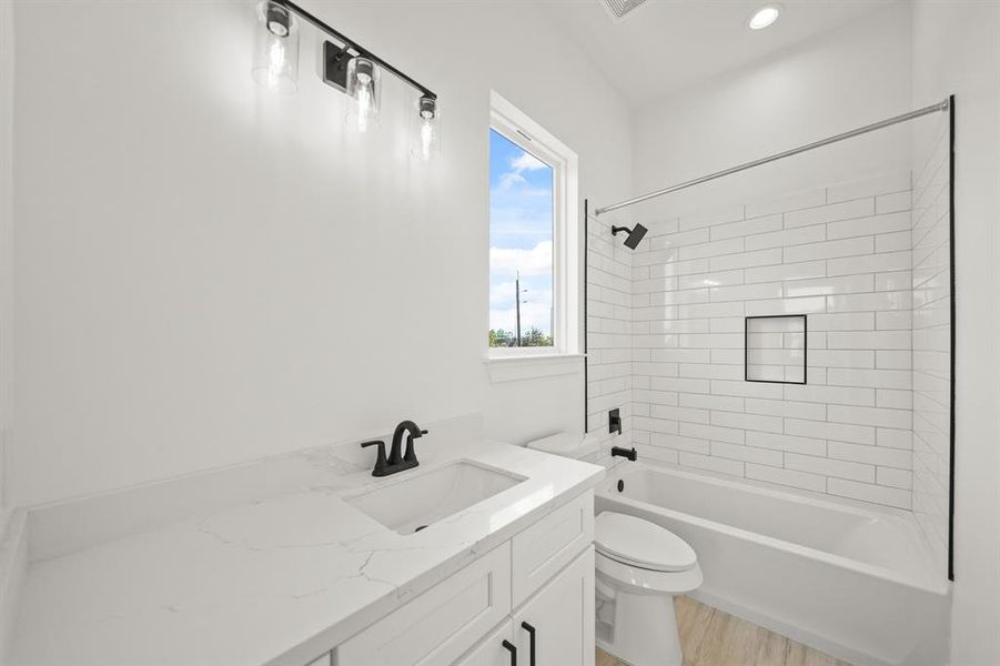 This bathroom is complete with tile floors, soft closing drawers, granite countertops, recessed lighting, and a shower/tub combo.