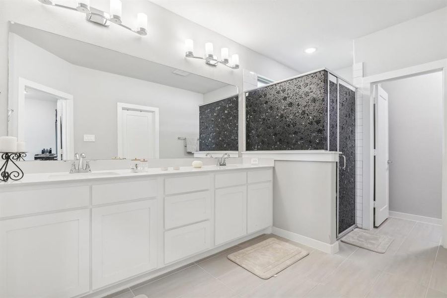 Bathroom featuring double vanity, walk in shower, and tile floors