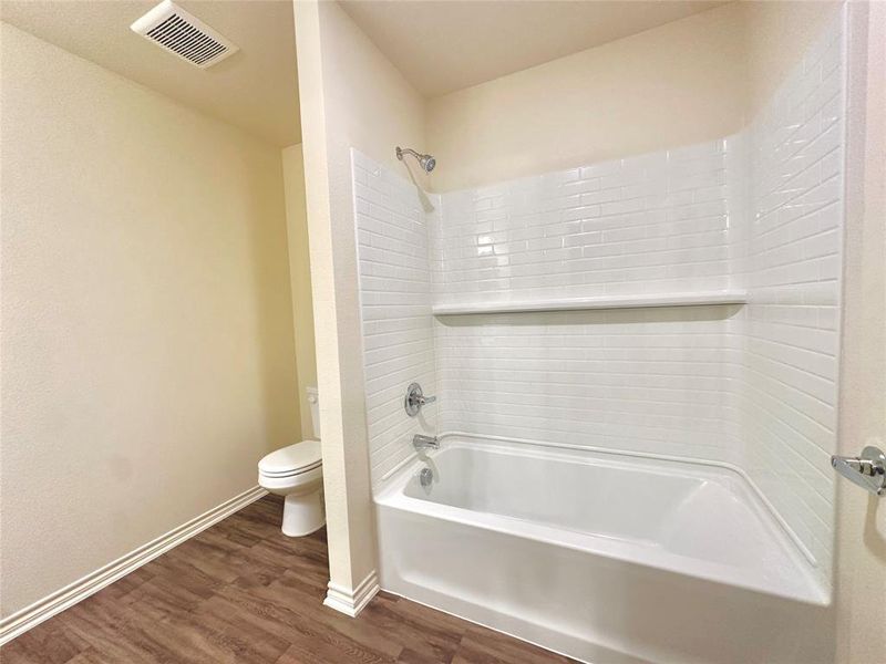 Bathroom featuring bathing tub / shower combination, wood-type flooring, and toilet