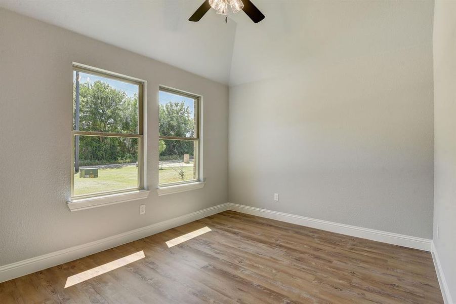 Empty room with ceiling fan, vaulted ceiling, and hardwood / wood-style floors