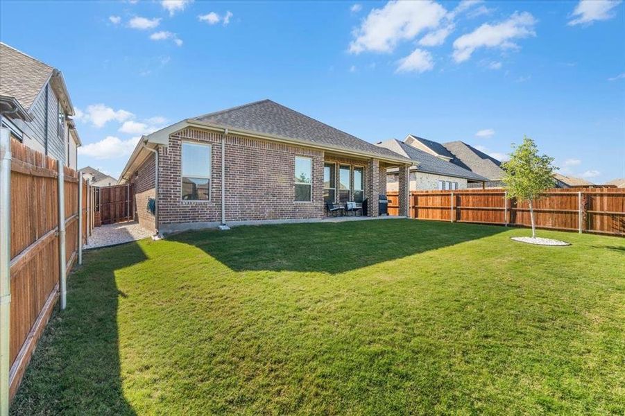 Back of property featuring a lawn and a patio area