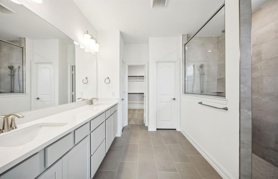 Spacious owner's suite with dual vanity and oversized shower*real home pictured