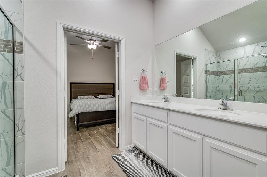 Bathroom with ceiling fan, hardwood / wood-style floors, lofted ceiling, an enclosed shower, and vanity