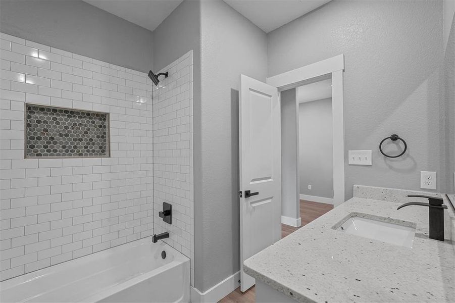 Bathroom featuring vanity, tiled shower / bath combo, and wood-type flooring