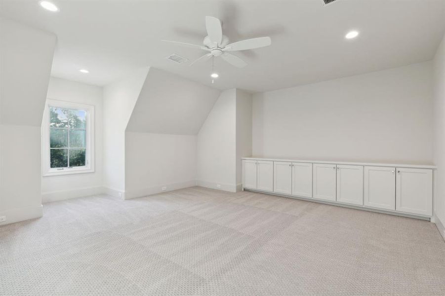 Bonus room featuring ceiling fan, lofted ceiling, and light colored carpet