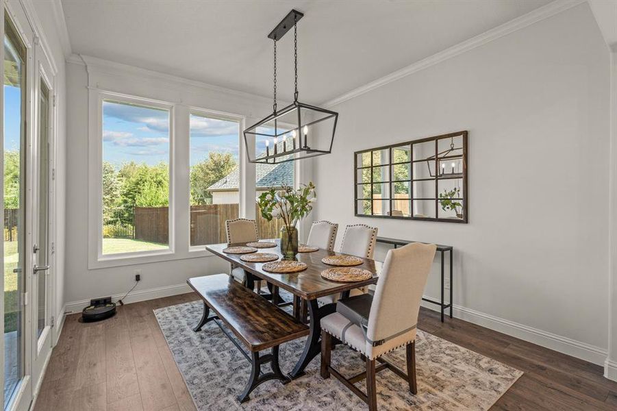 Dining area with ornamental molding, dark wood-type flooring, and a chandelier