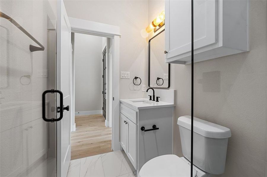 Bathroom featuring wood-type flooring, a shower with shower door, vanity, and toilet