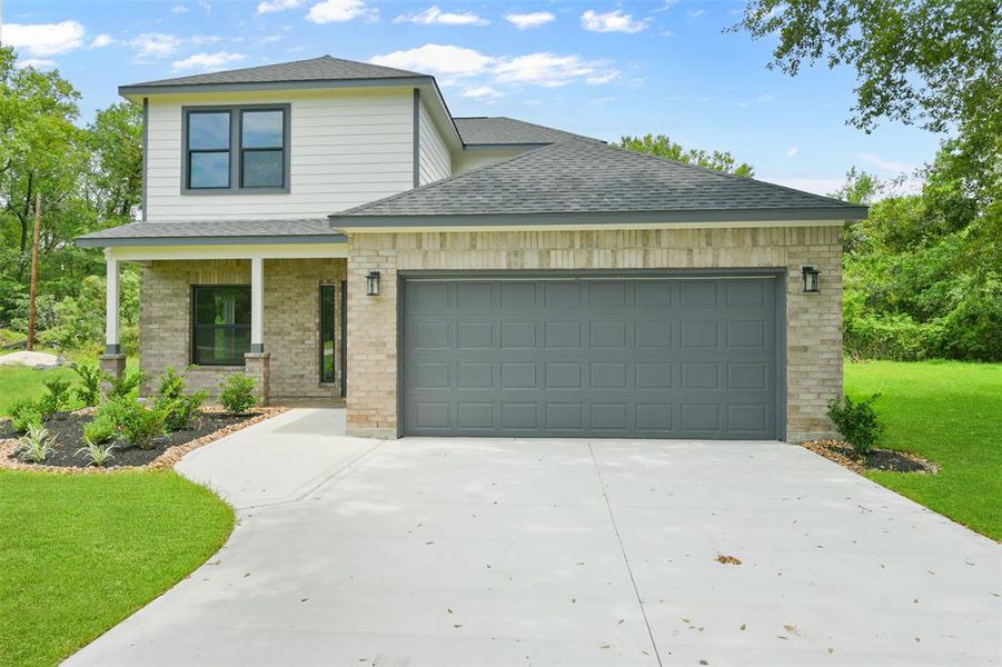 This two-story home featuring a mix of brick and siding exterior, with a prominent two-car garage with a long driveway.