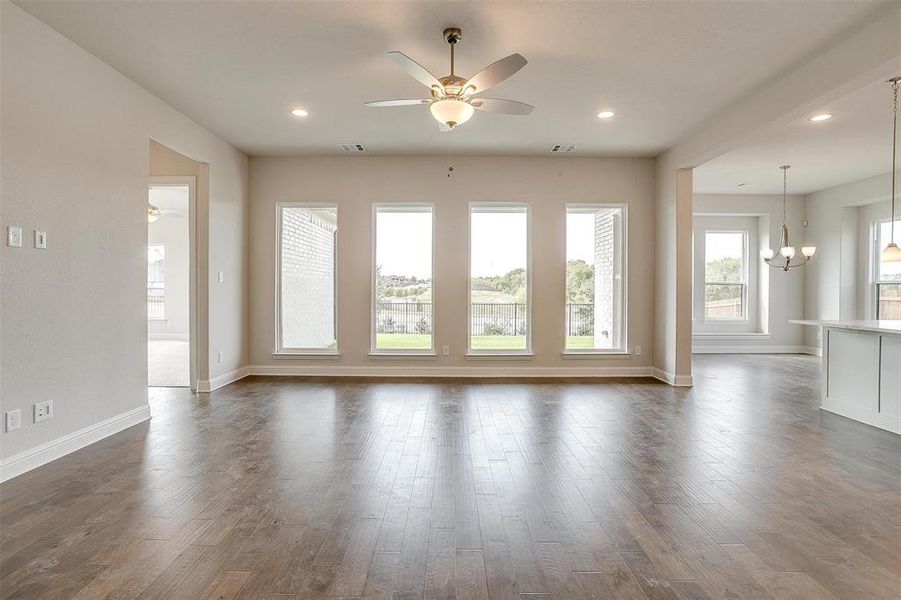 Unfurnished room with ceiling fan with notable chandelier and dark hardwood / wood-style flooring