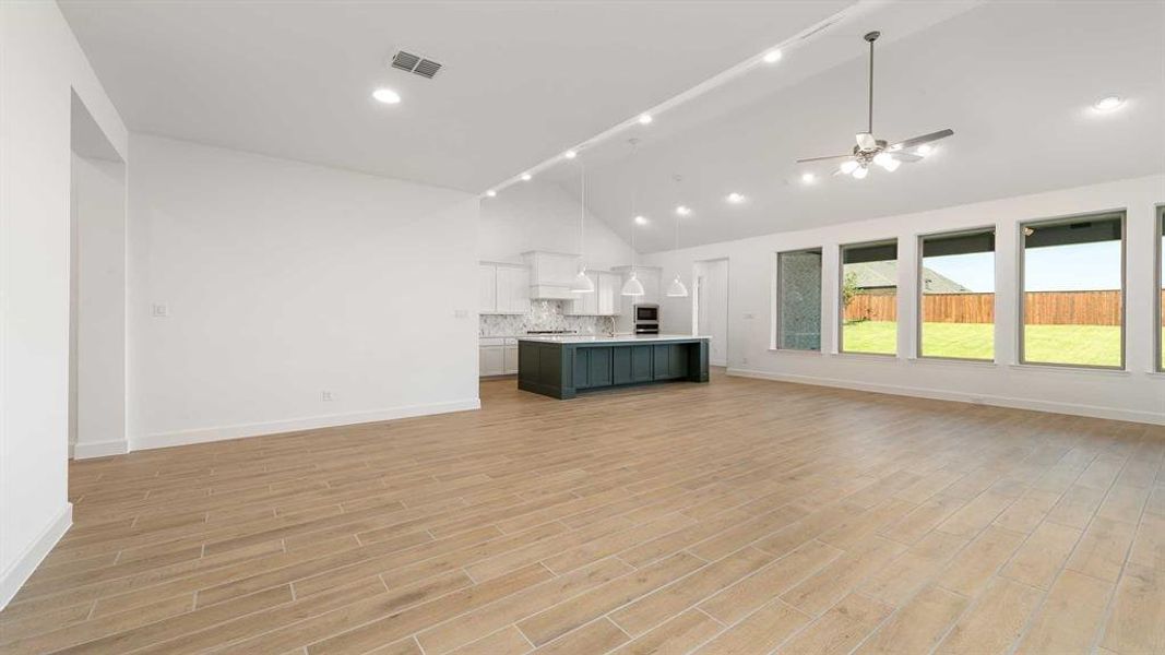 Unfurnished living room featuring light hardwood / wood-style flooring, high vaulted ceiling, and ceiling fan