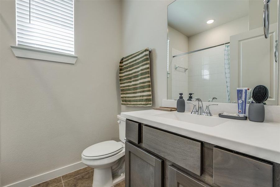 Bathroom featuring vanity, tile patterned floors, toilet, and a shower with shower curtain