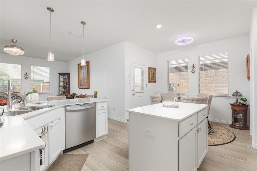 Kitchen with dishwasher, light hardwood / wood-style floors, and a center island